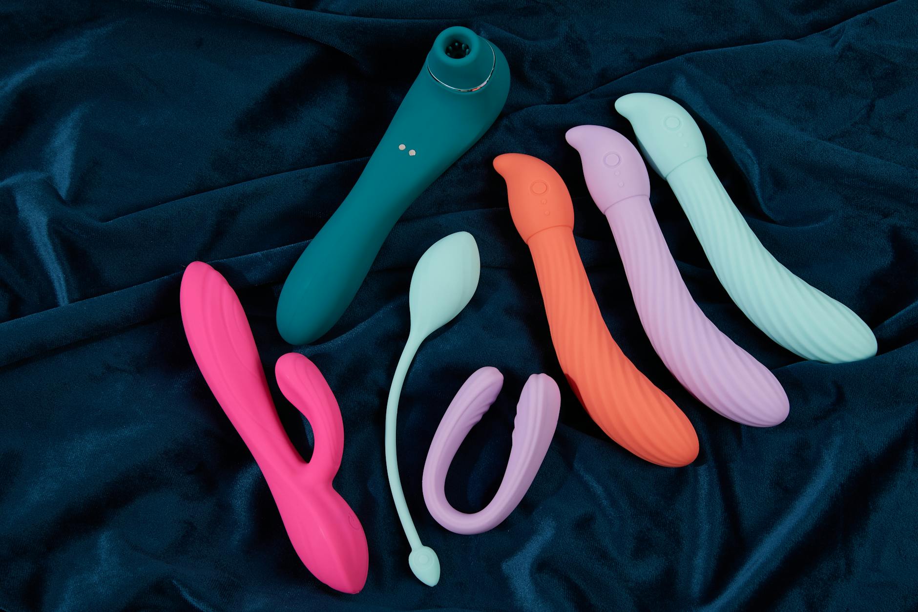 Hand holding an orange vibrator against a purple backdrop