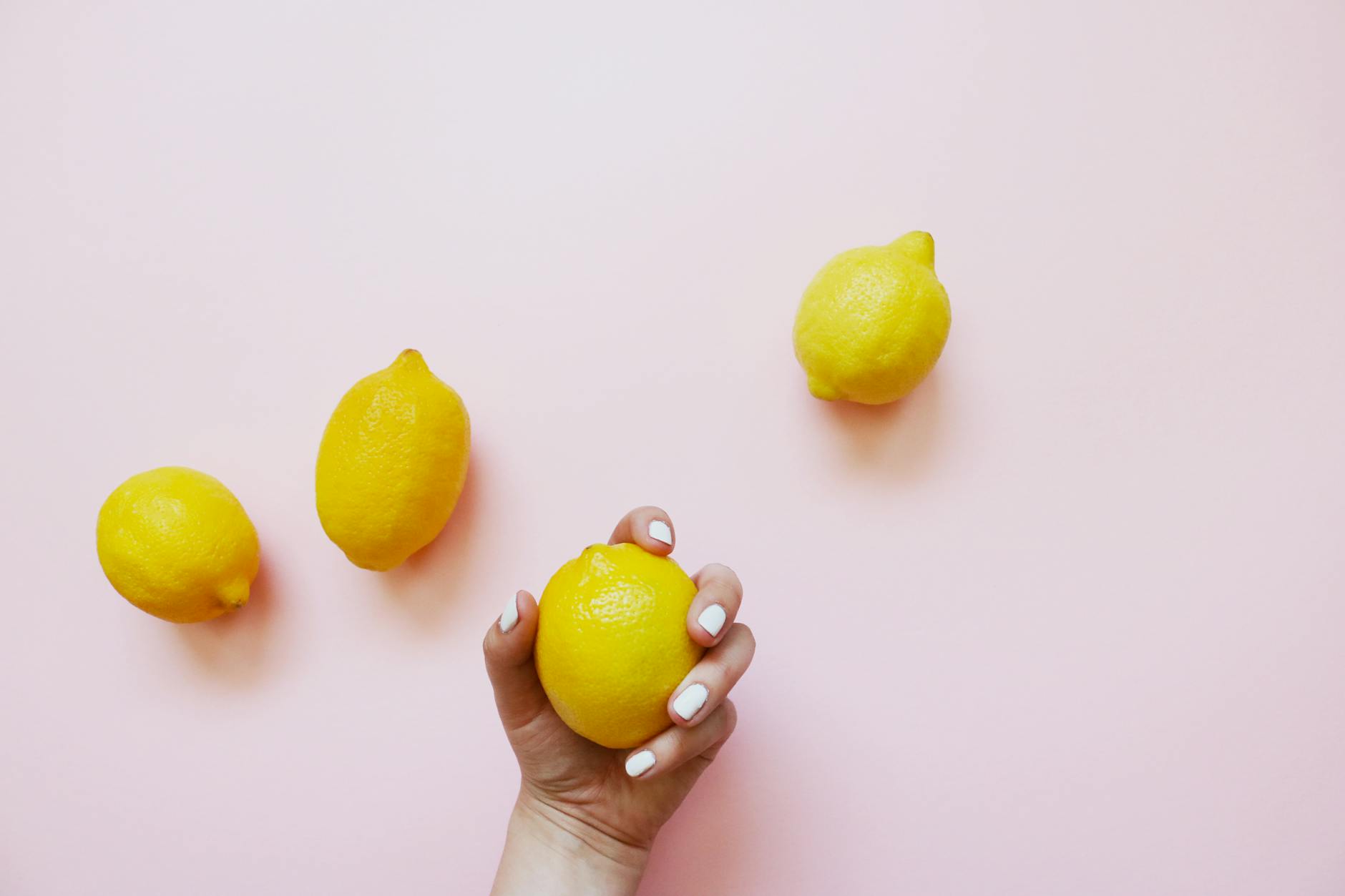 Two hands gently cupping fresh lemons on a brown surface, symbolizing care and renewal