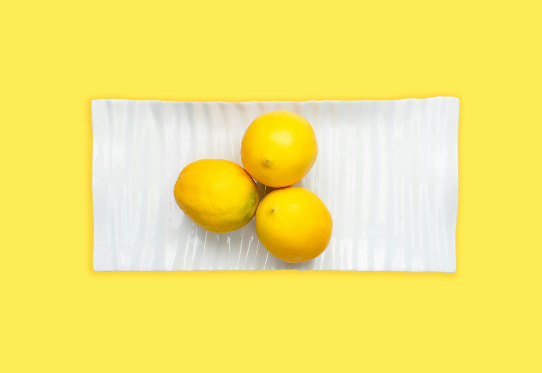 Hand holding a lemon vibrator against a minimalist purple background