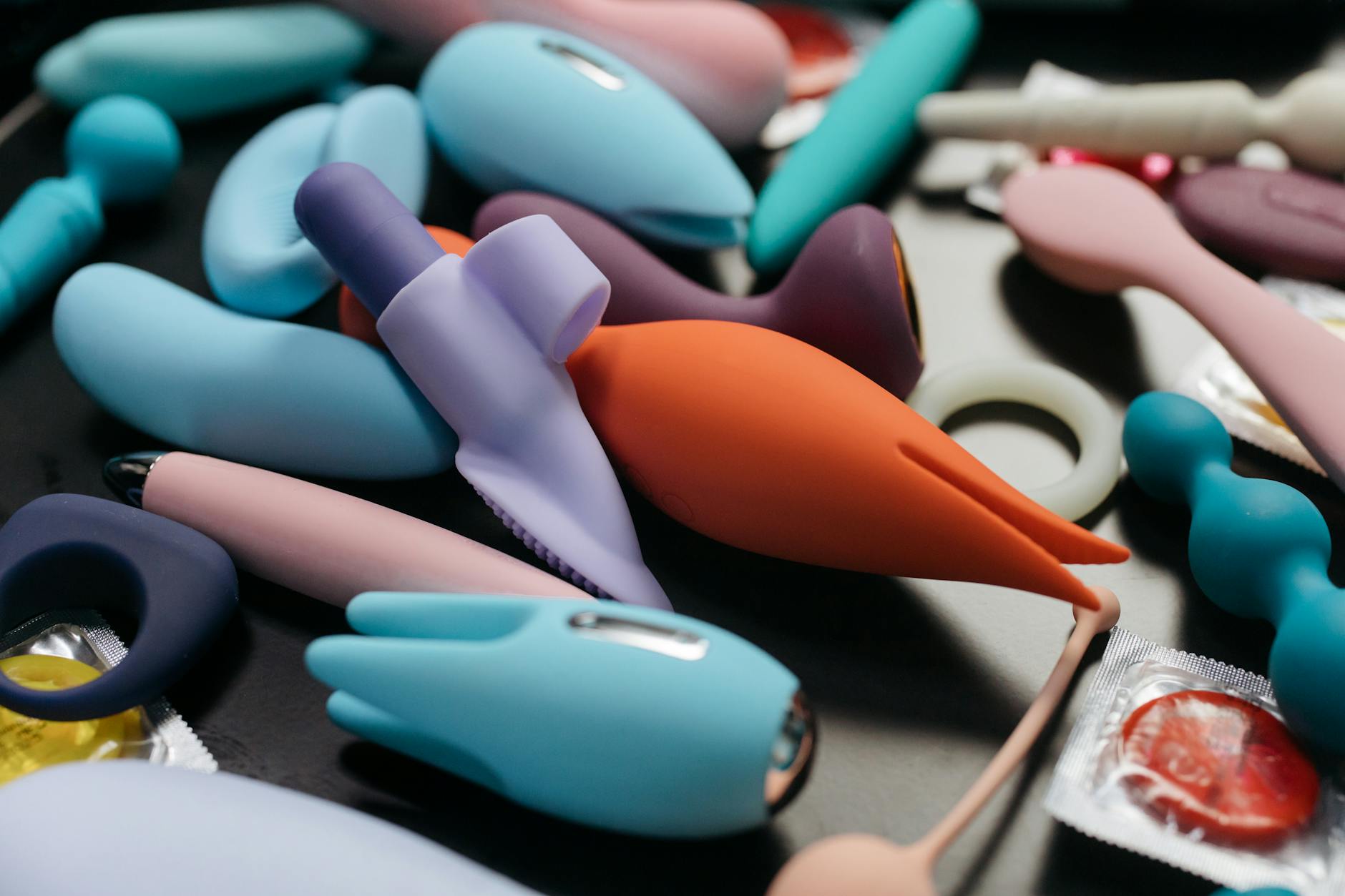 Trois vibrateurs colorés disposés sur un tissu blanc, mettant en avant leur texture lisse.