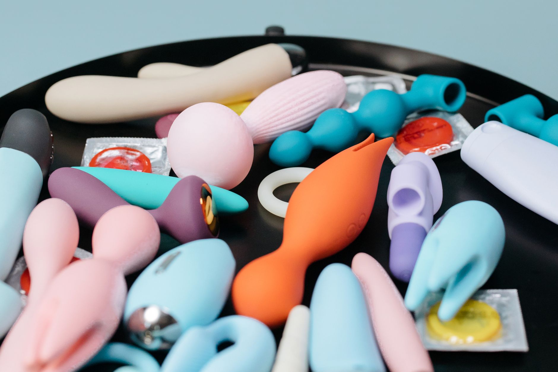 Collection de jouets sexuels de couleurs variées sur plateau noir, mettant en évidence les différentes formes et designs des vibrateurs
