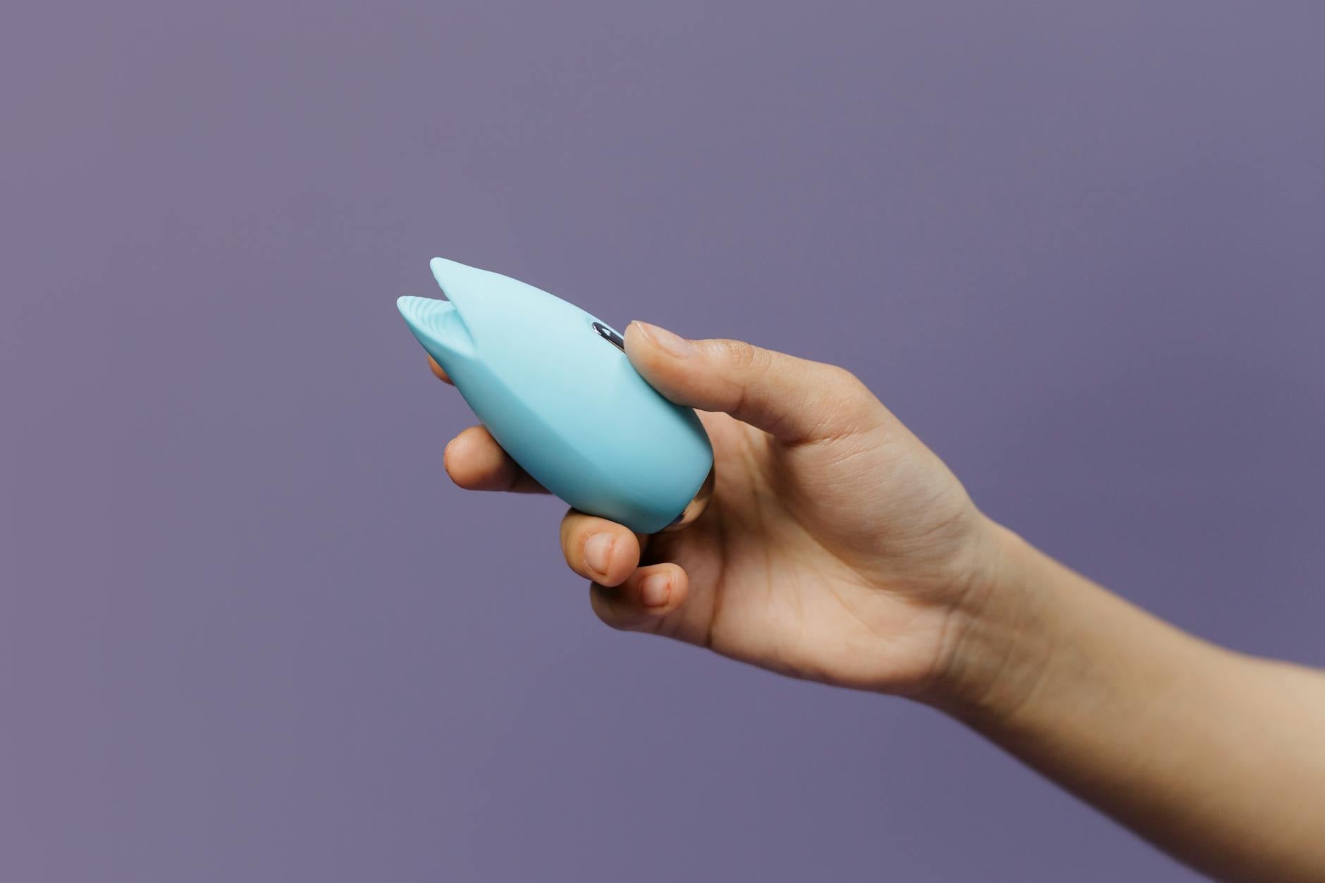 A blue silicone lemon vibrator held in hand against a solid background, promoting self-pleasure and sexual wellness