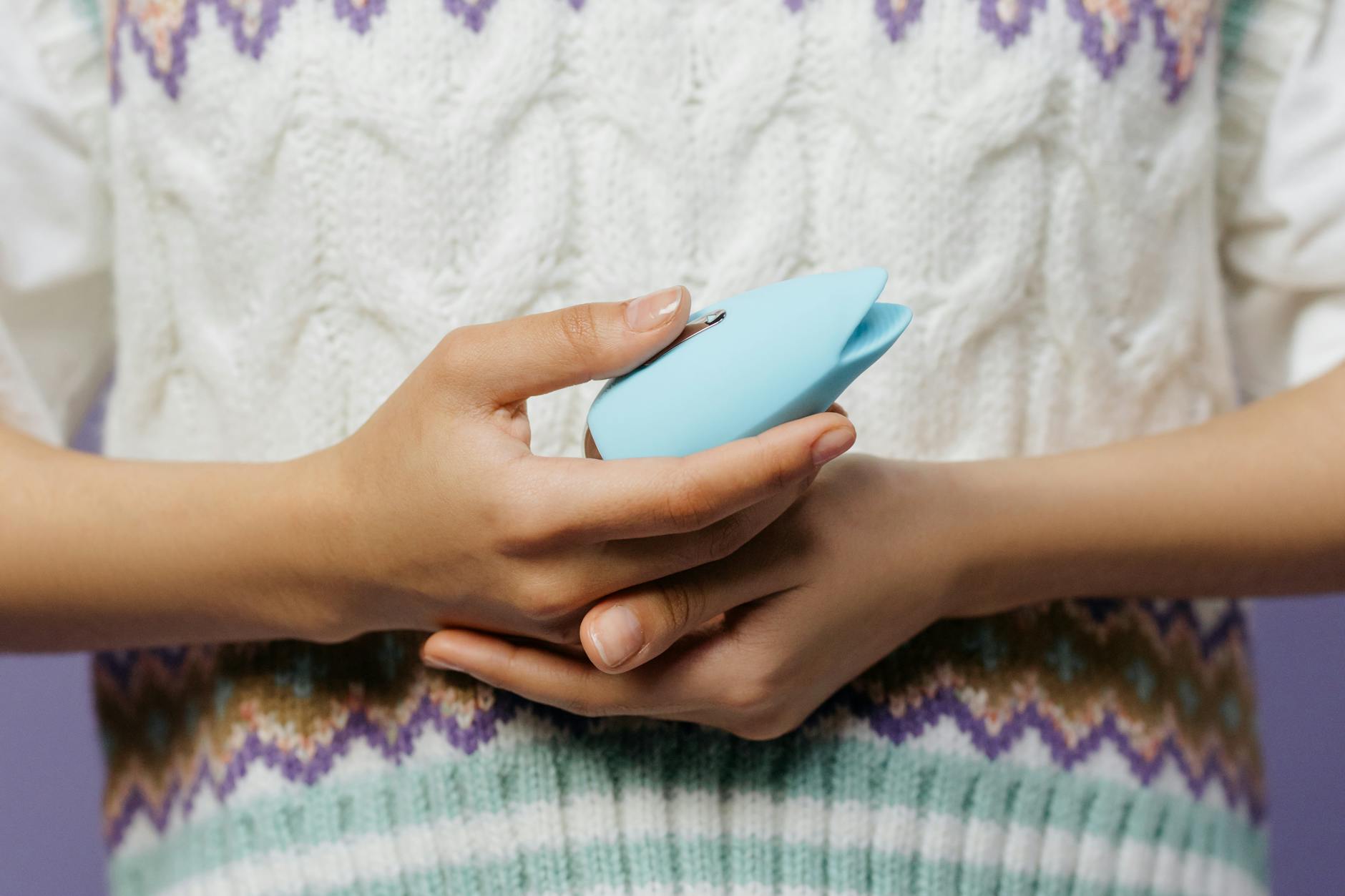 Woman holding two colorful vibrators against a purple background, representing openness about pleasure in relationships.